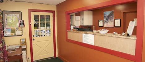 A reception area with a desk, a bulletin board, and a door.