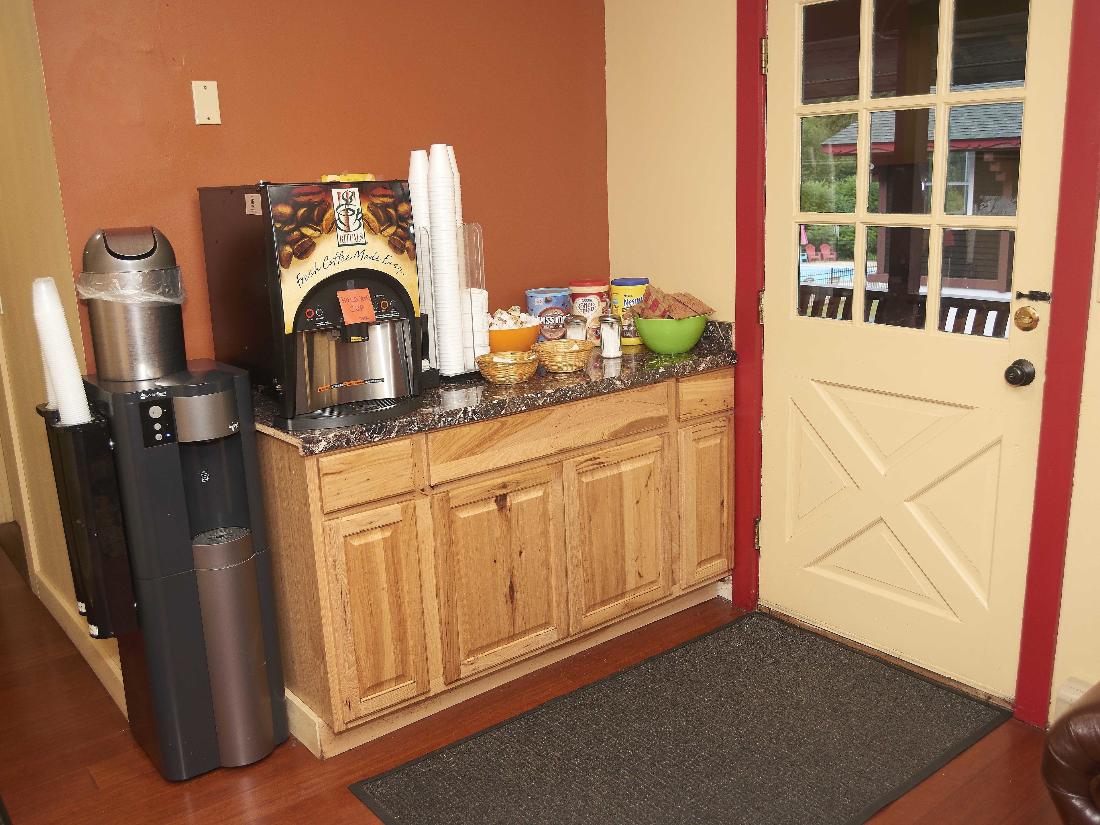 A kitchen area with a coffee maker, a trash can, and various food items on the counter.