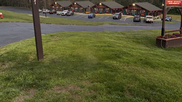 A lodge with multiple cabins, a parking lot, and a sign indicating amenities like a fireplace, not-to-suites, and a heated outdoor pool.