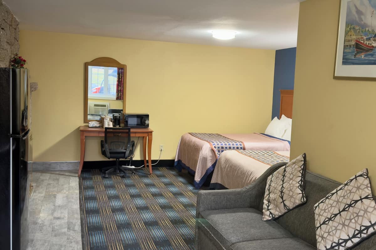 A hotel room with a bed, a desk with a computer, a chair, and a couch.