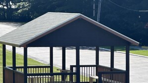 A gazebo with a sloped roof and wooden benches.