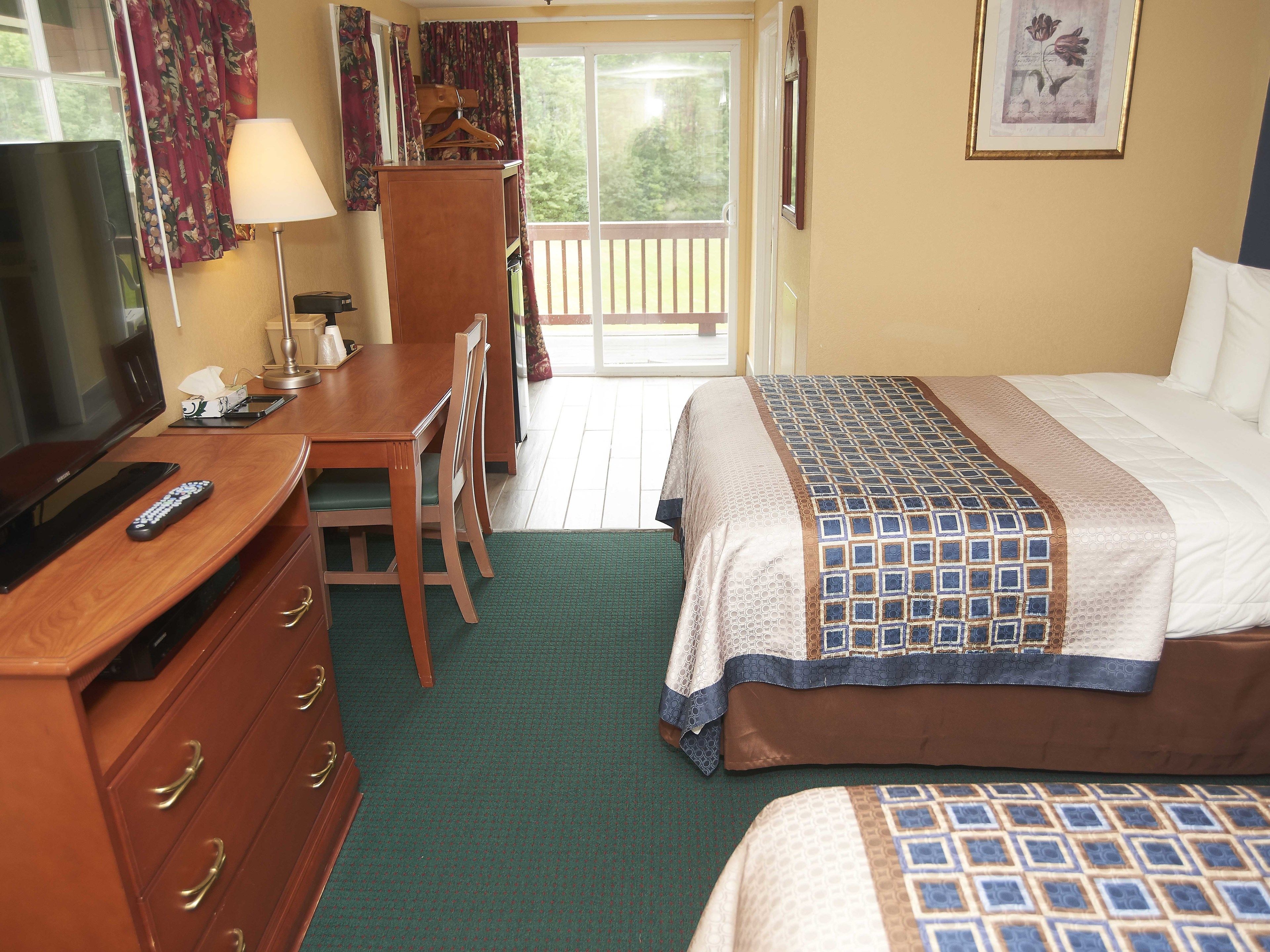 A hotel room with a bed, a desk, a television, and a balcony.