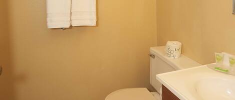 A bathroom with a toilet, a sink, and a towel rack with two towels.