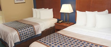 A hotel room with two beds, a nightstand with a lamp, and a framed picture on the wall.