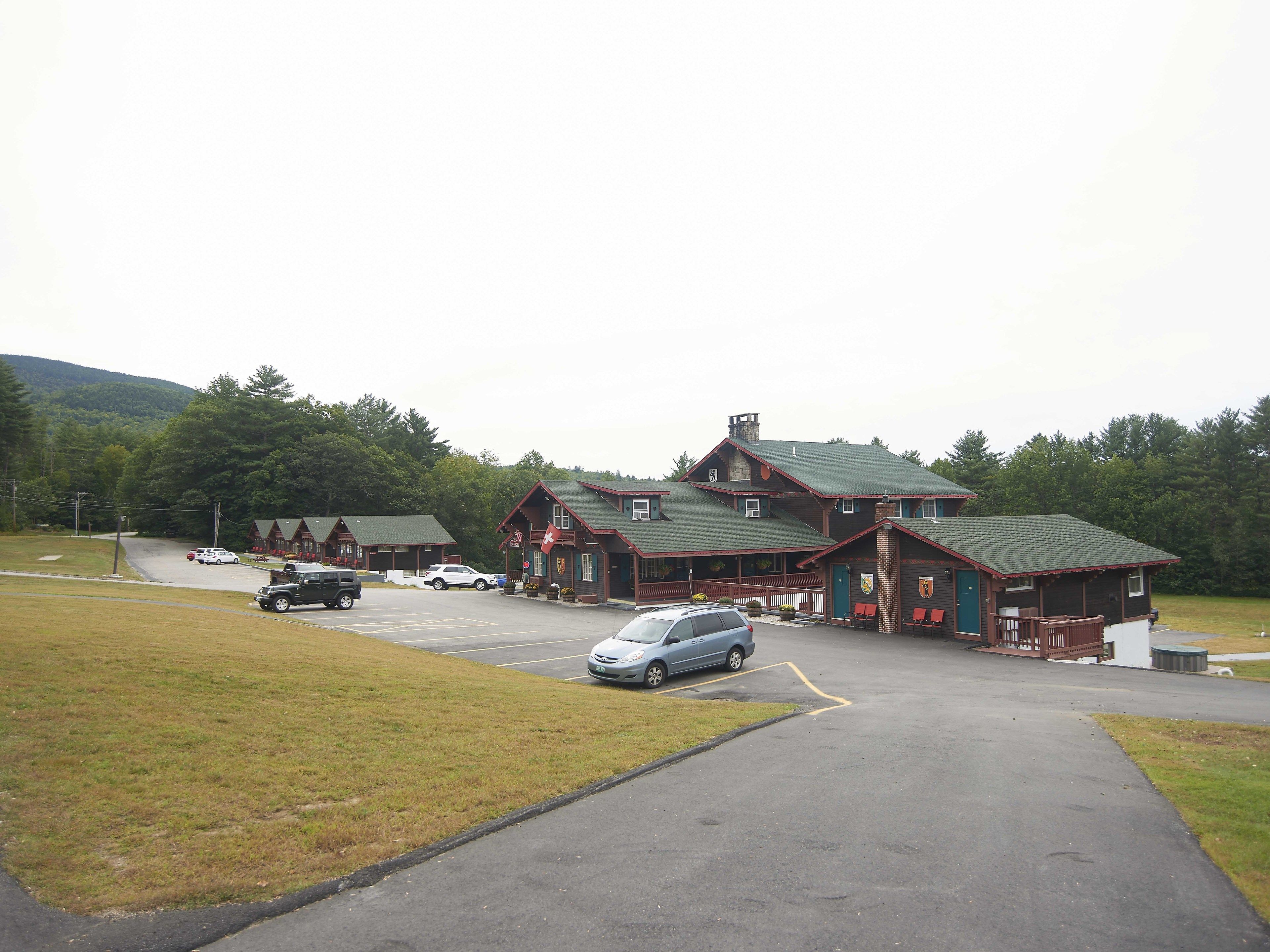 A lodge with a large parking area and a main building with a green roof.