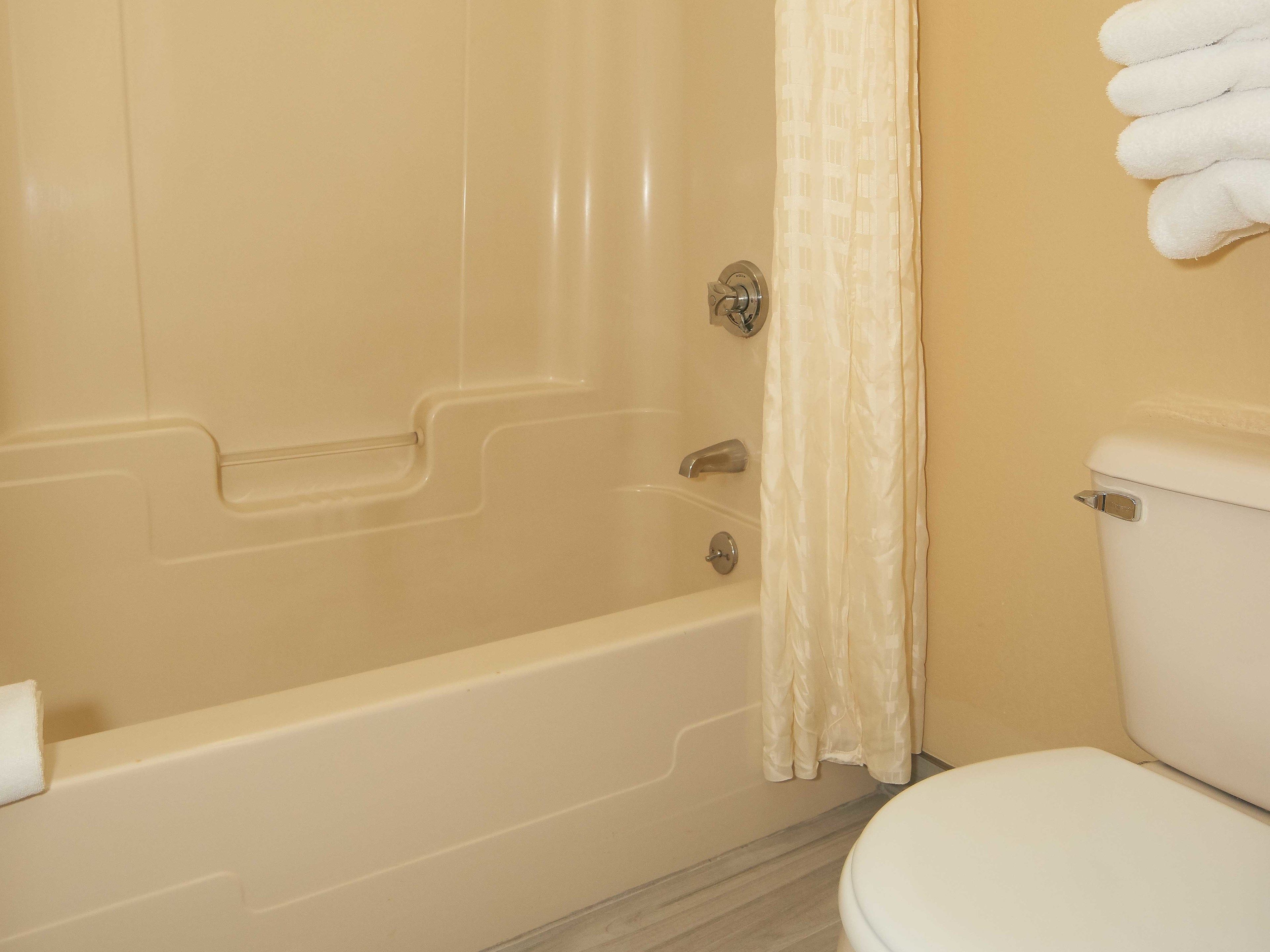 A bathroom with a bathtub, toilet, and a towel rack.