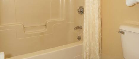 A bathroom with a bathtub, toilet, and a towel rack.