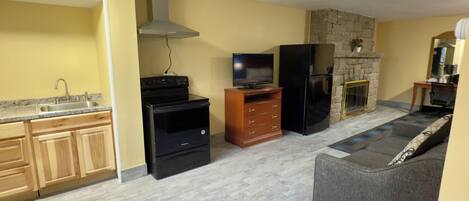 Un espacio habitable compacto con cocina, chimenea, sofá y televisor.