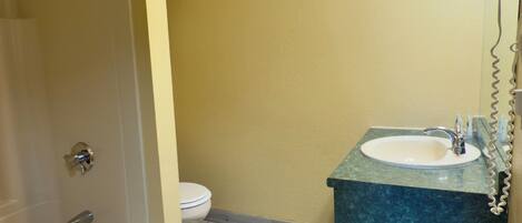 A bathroom with a shower, toilet, sink, and vanity.