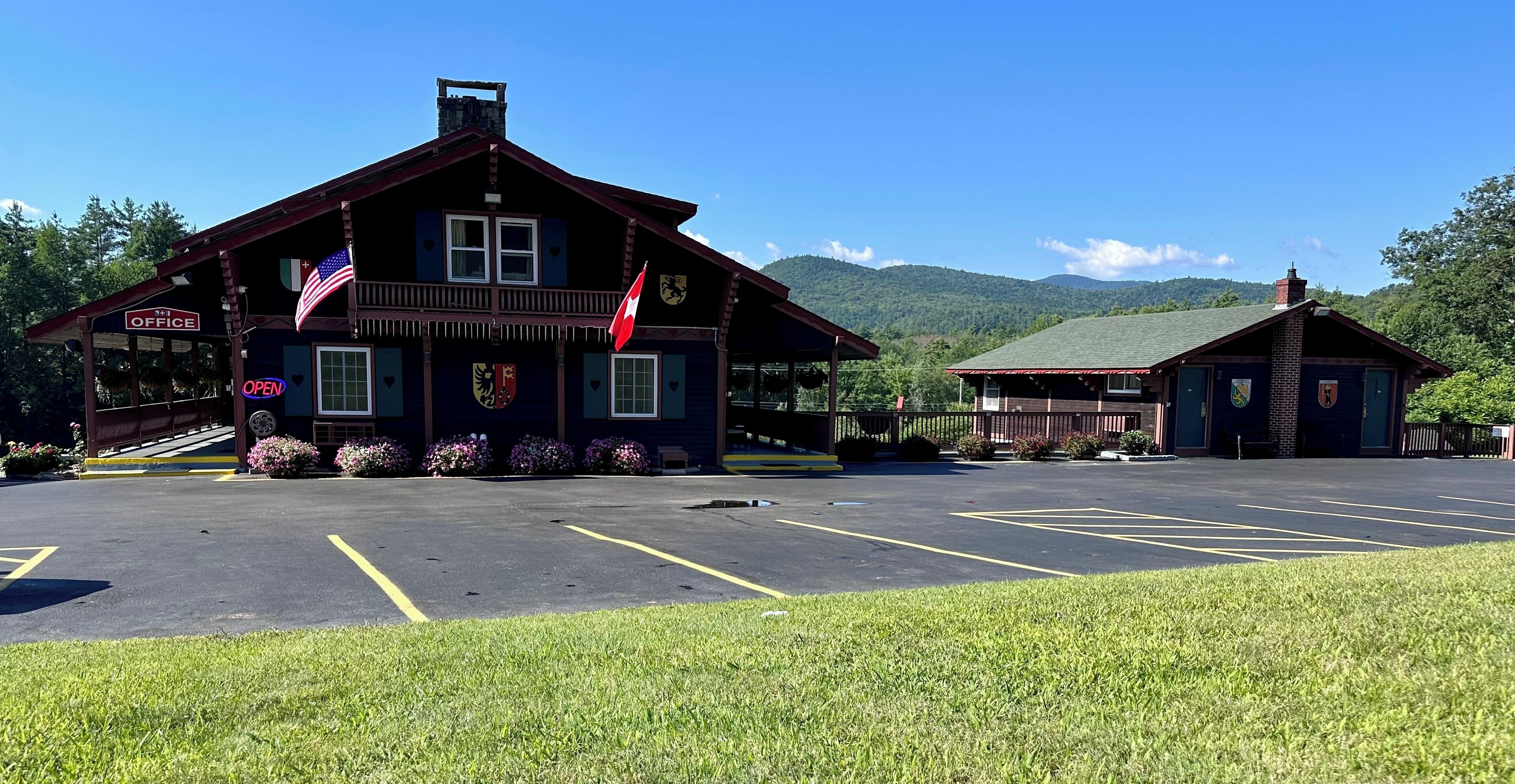 A lodge with a porch, an American flag, and a sign indicating it's open.