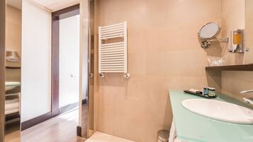 Un baño moderno con un lavabo de vidrio, un toallero blanco y un espejo.