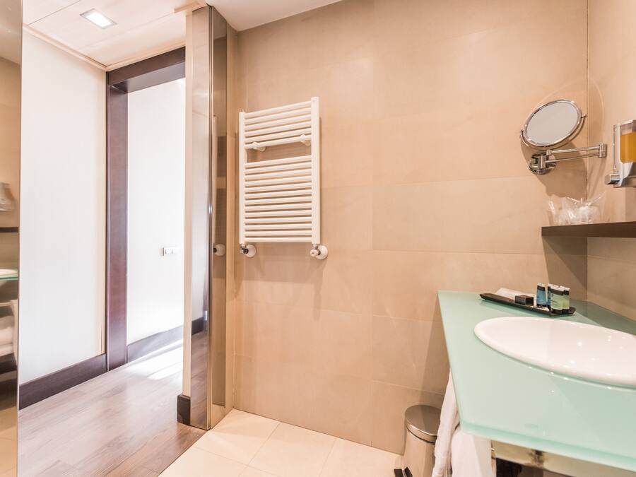 Un baño moderno con un lavabo de vidrio, un toallero blanco y un espejo.