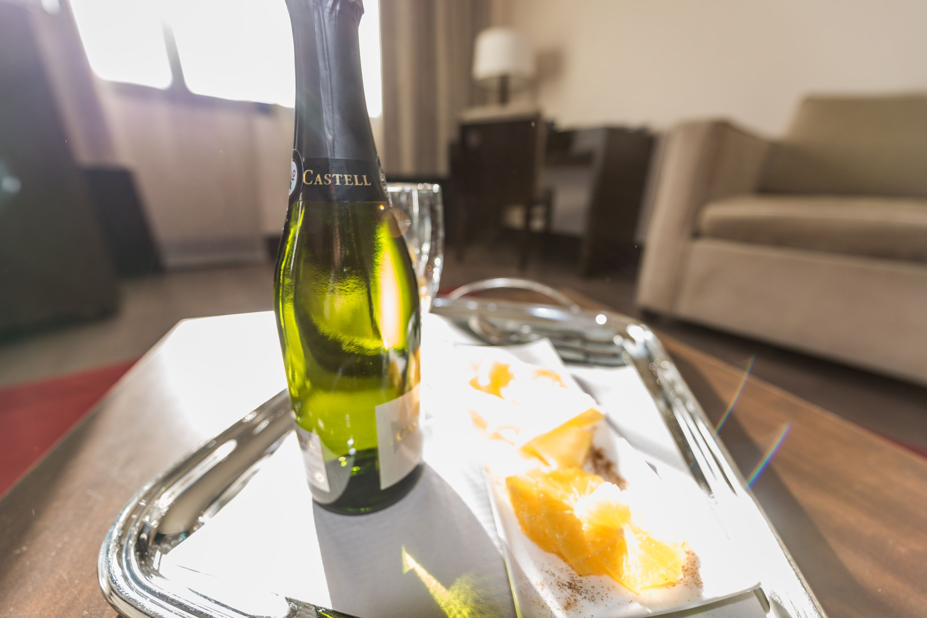 A bottle of Castell wine on a tray with a glass and a piece of orange.