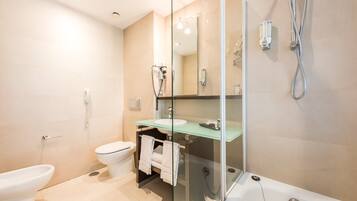 A modern bathroom with a glass-enclosed shower, a toilet, and a bathtub.