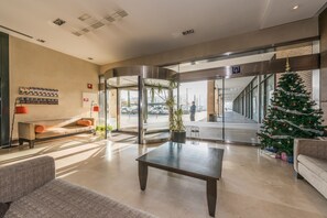 Un vestíbulo con mostrador de recepción, un árbol de Navidad y una entrada con puerta de vidrio.