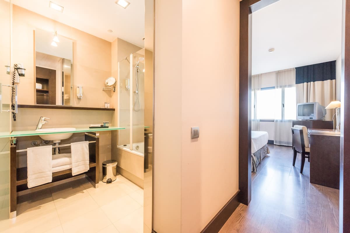 A modern bathroom with a glass shower enclosure, a sink with a mirror, and a toilet.