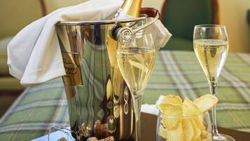 A table with a bottle of champagne, two champagne flutes, and a glass of chips.