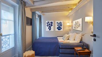 Una habitación de hotel con una cama, un sofá, una mesita y obras de arte en las paredes.