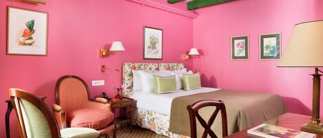 Una habitación con cama, dos sillas, una mesa y una lámpara.