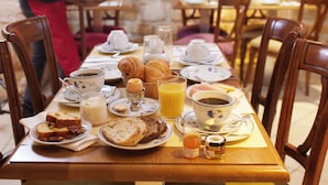 A breakfast table set with croissants, bread, eggs, and beverages. - Le Relais Montmartre (Paris)