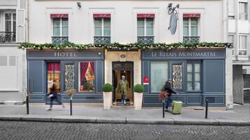 Fachada de hotel con estilo arquitectónico europeo clásico, que presenta una entrada central, detalles de hierro decorativo y un cartel con el nombre del hotel.