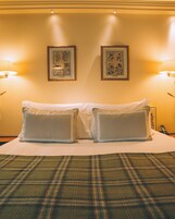 A hotel room with a large bed, two wall-mounted lamps, and two framed floral artworks.