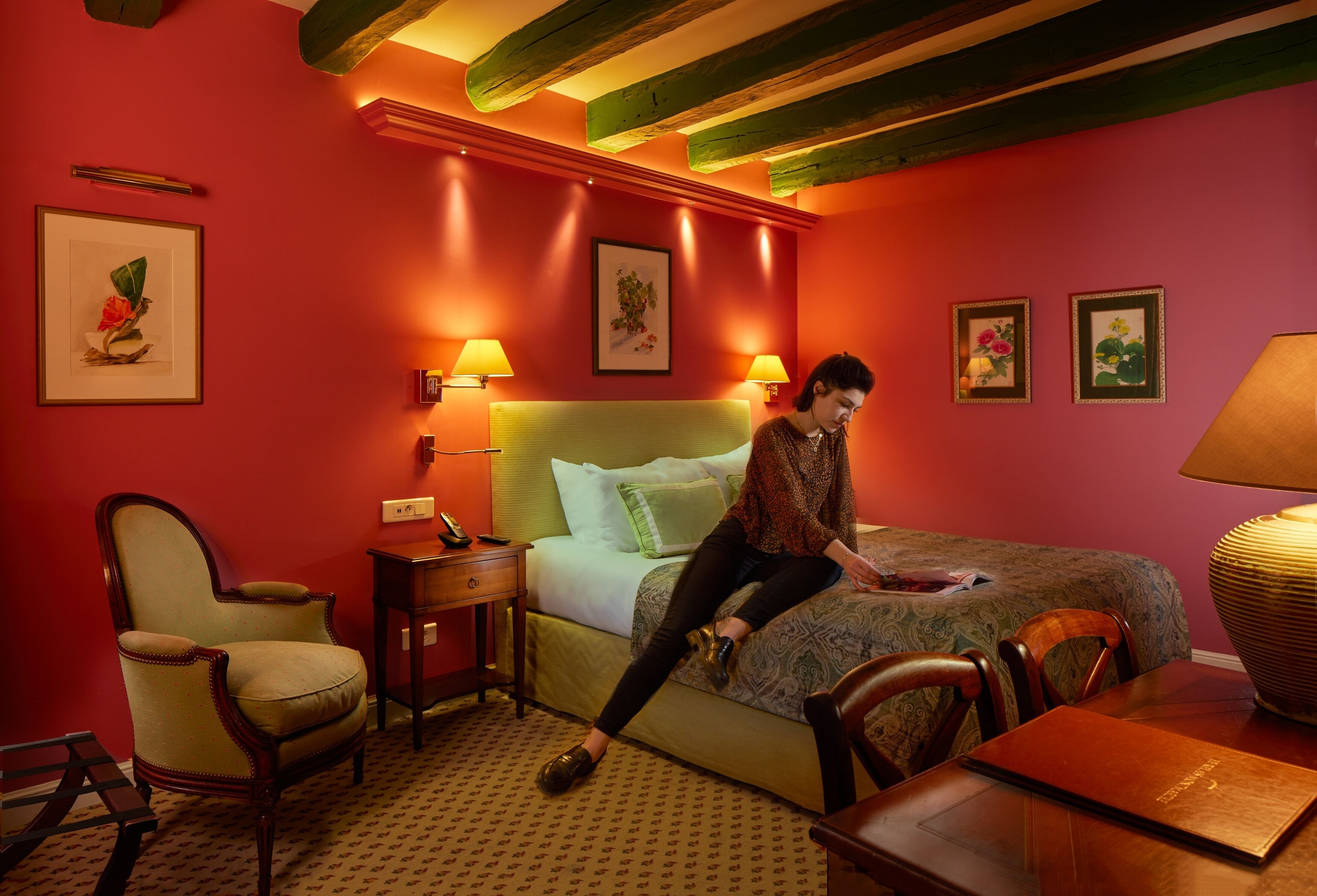 Una habitación de hotel con una cama, una silla, una mesa y dos lámparas de noche.