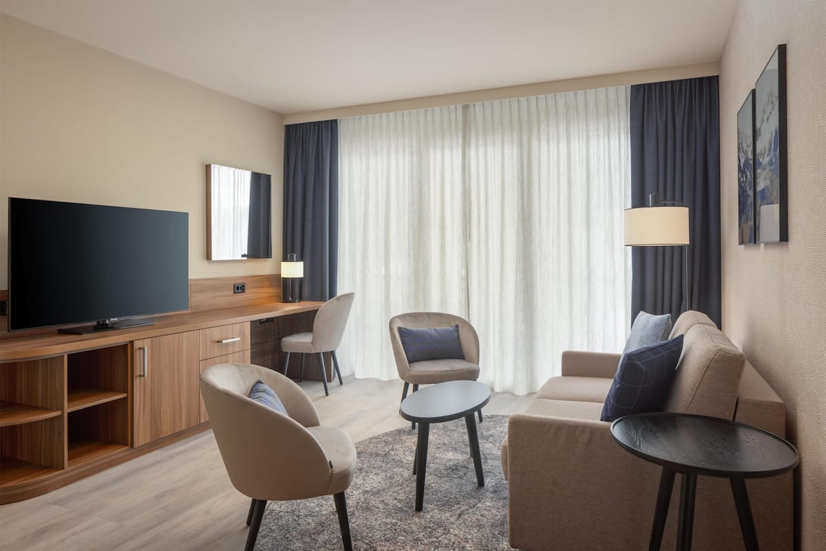 Suite junior, 1 cama King size | Área de sala de estar | Televisión de pantalla plana de 55 pulgadas con canales vía satélite