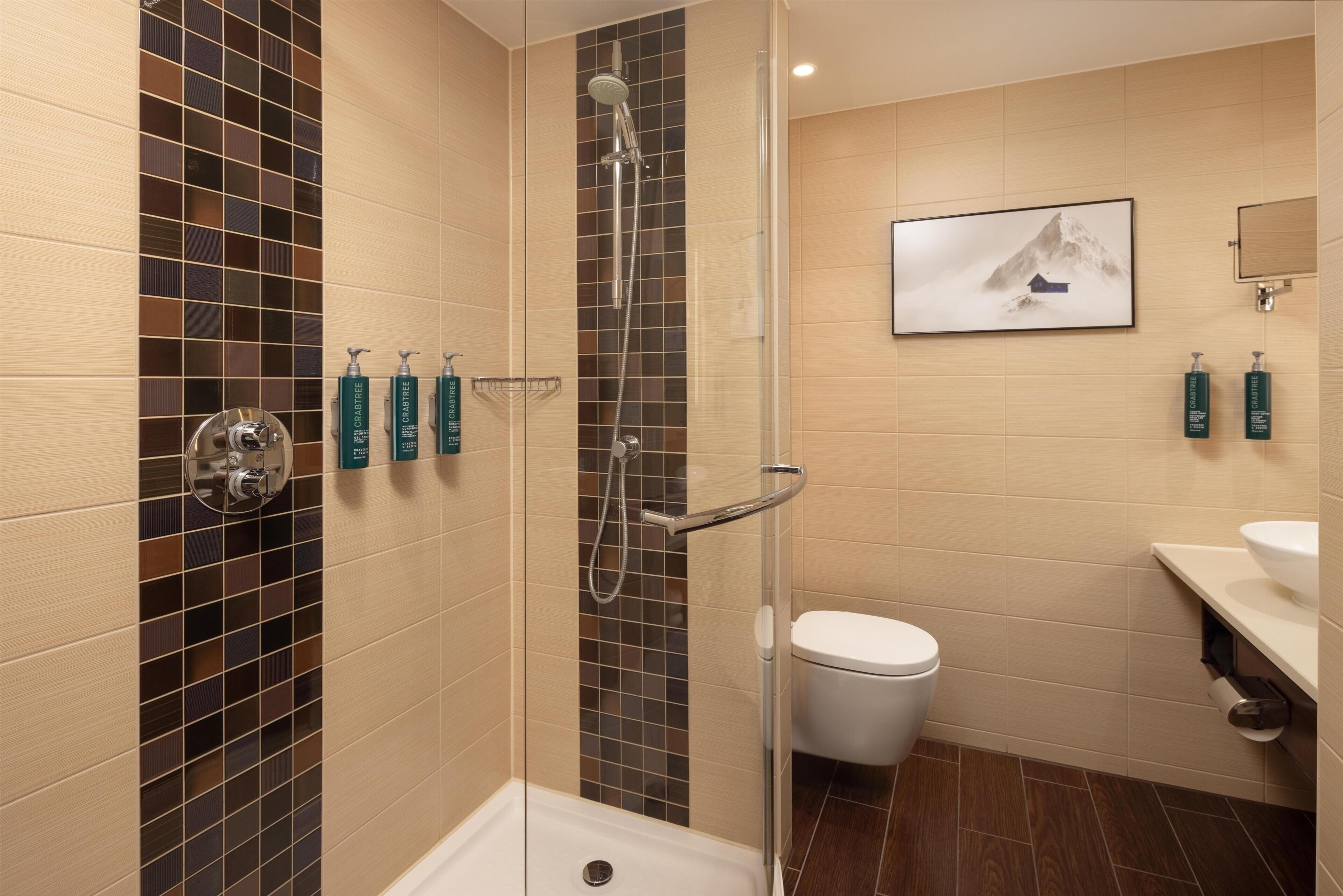 A modern bathroom with a glass-enclosed shower, a toilet, and a sink.