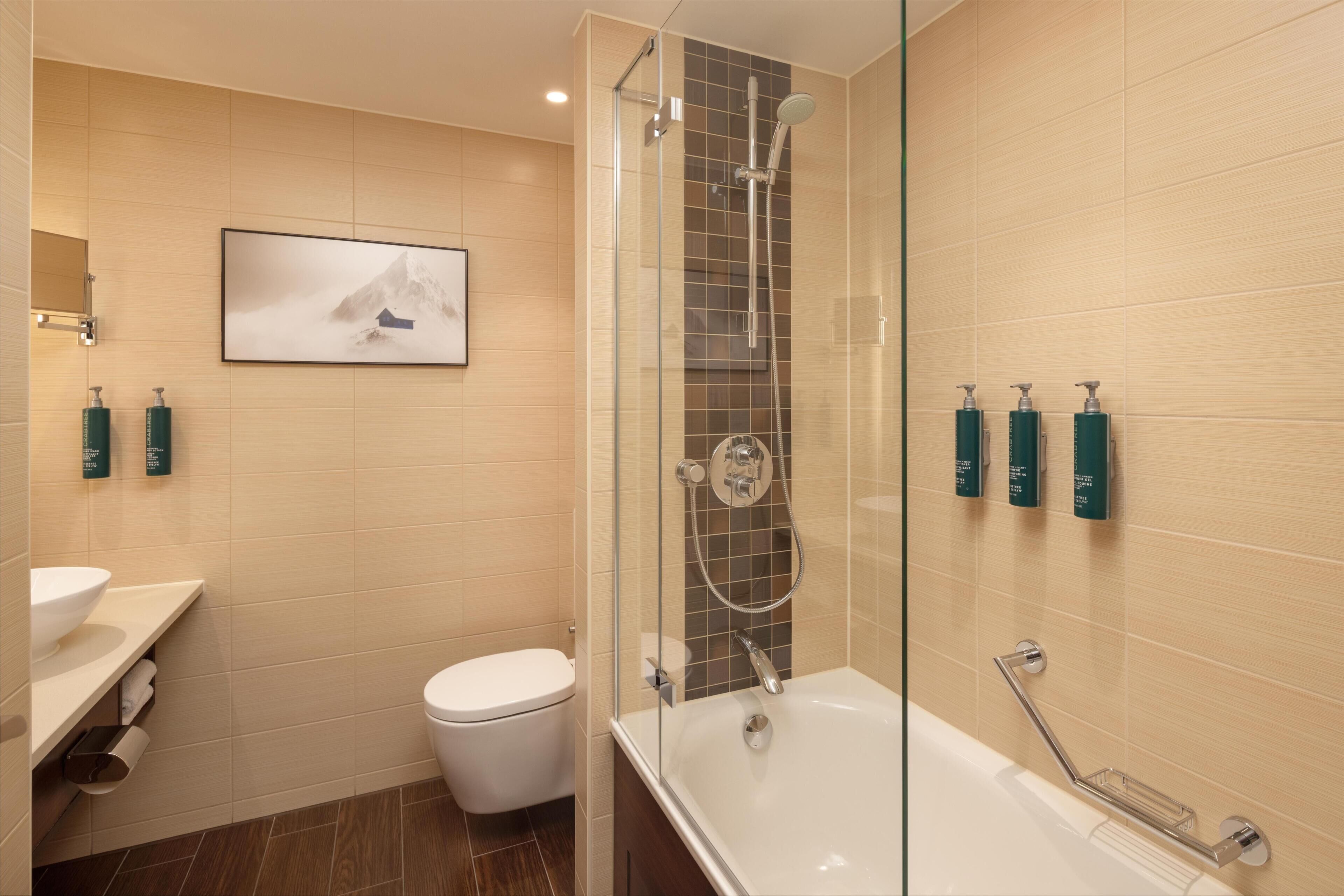 Une salle de bain moderne avec une douche à parois de verre, des toilettes, un lavabo et un tableau encadré au mur.