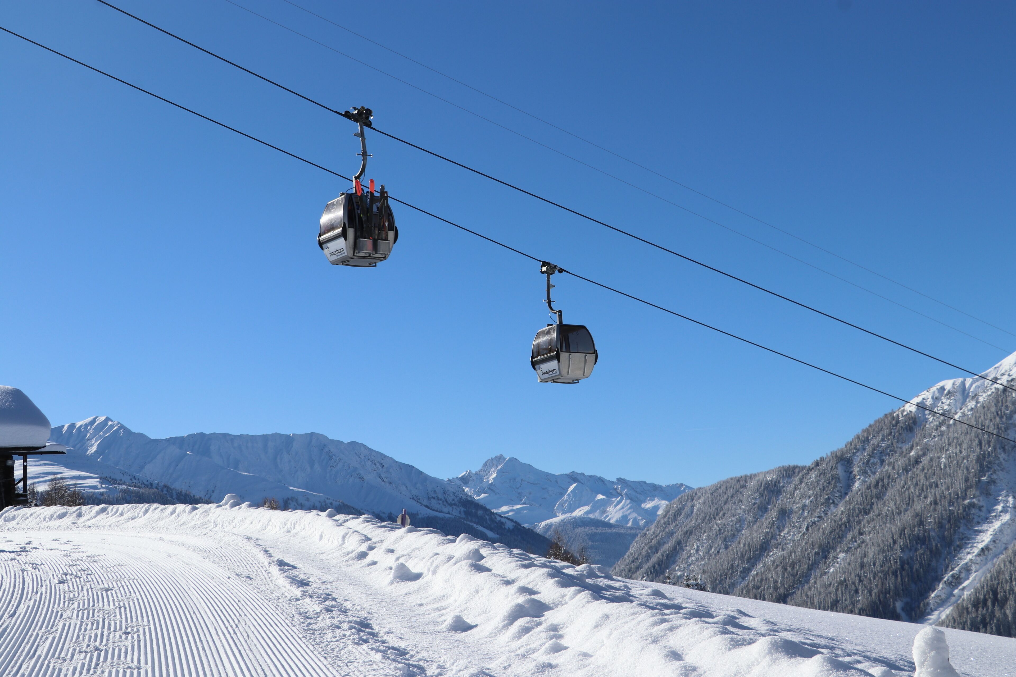 A ski lift with cabins suspended by cables against a clear blue sky.