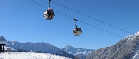 A ski lift with cabins suspended by cables against a clear blue sky.