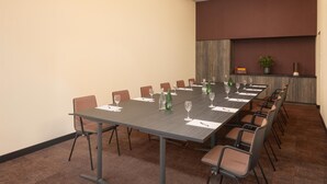 A conference room with a long table, chairs, and a plant on a shelf. - Hilton Garden Inn Davos (Davos)