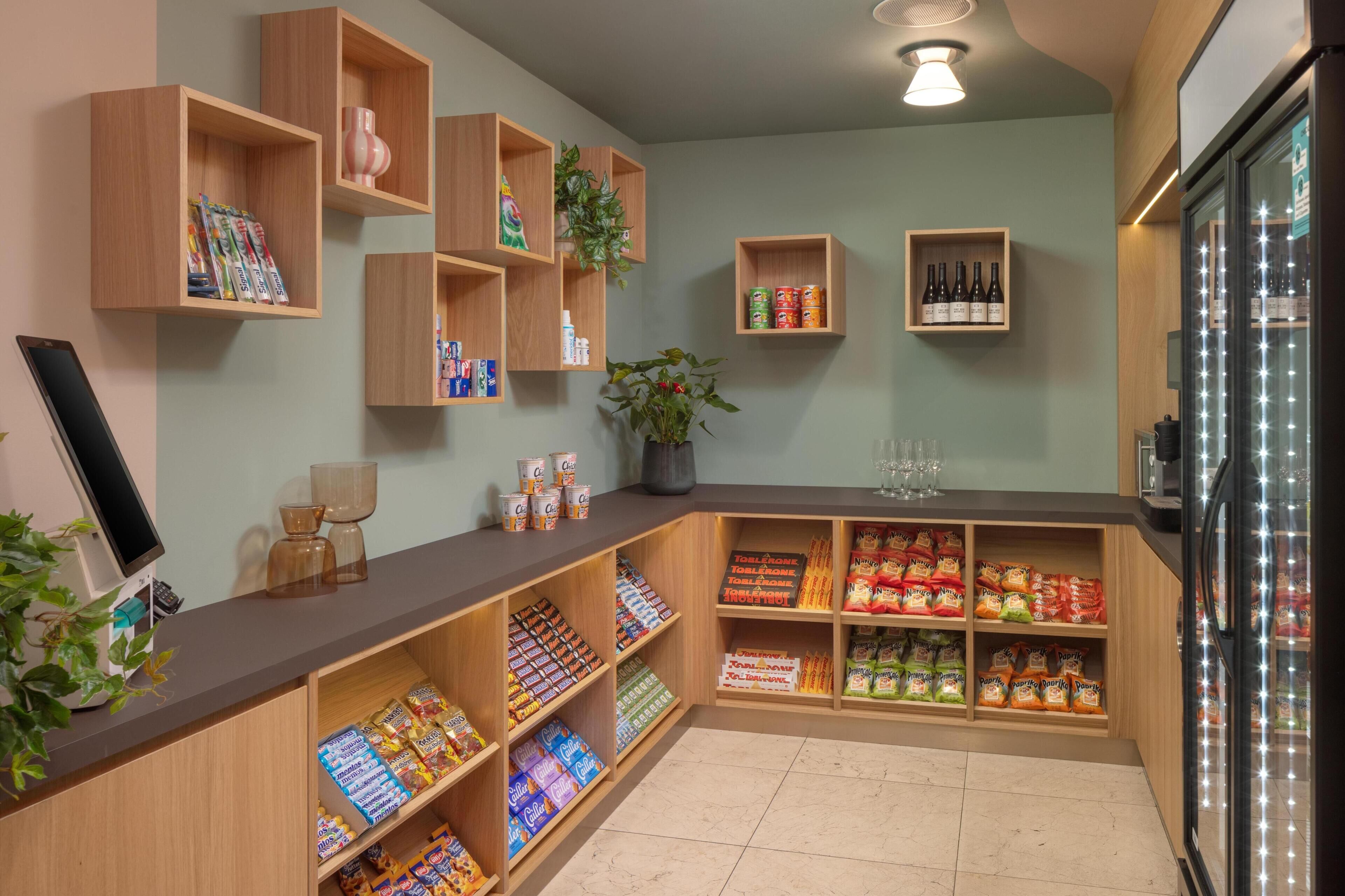 Ein Geschäft mit Holzböden, gefüllt mit Snacks und Getränken, einer Kasse und einem Kühlschrank.