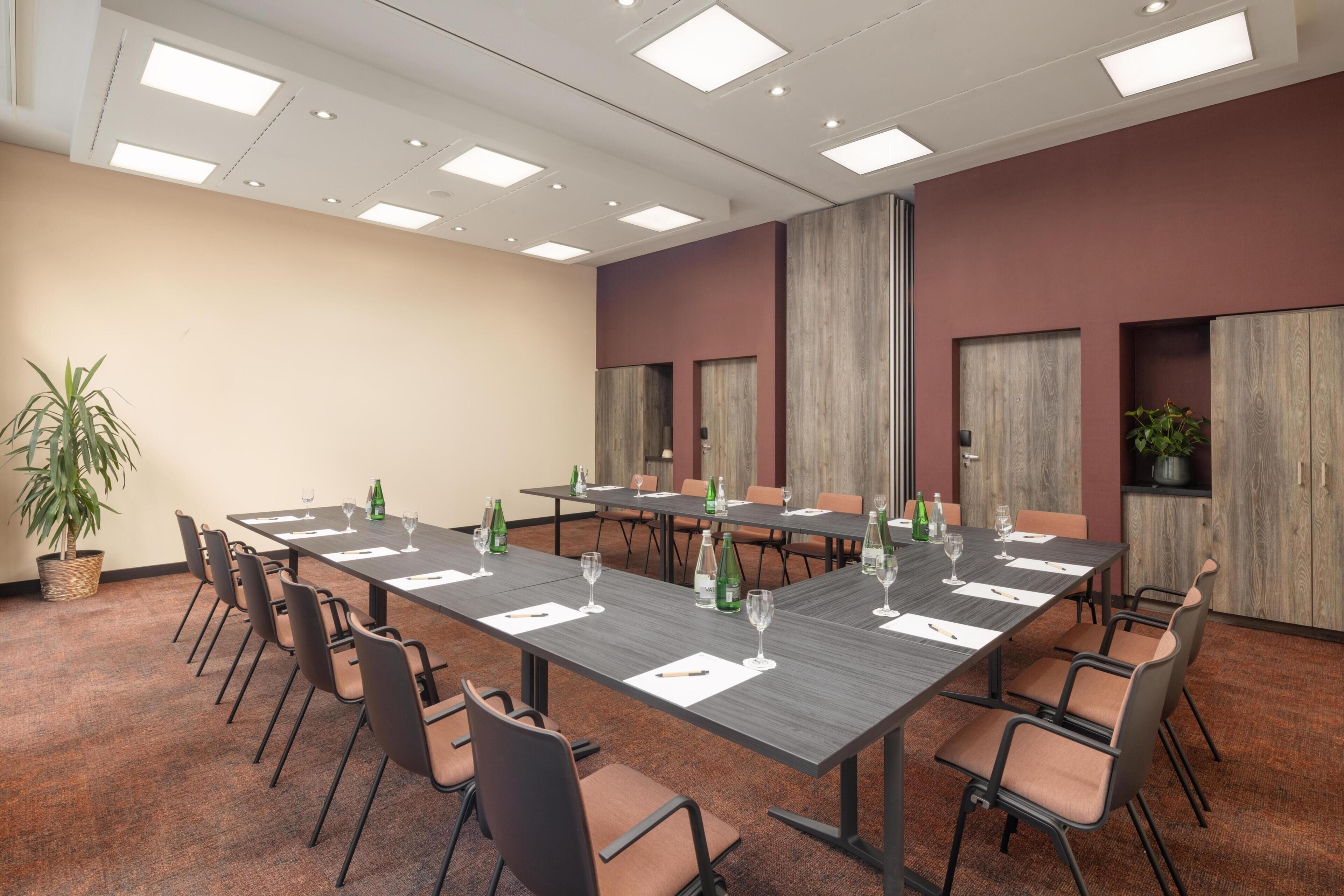 A conference room with a long table, chairs, and a potted plant.