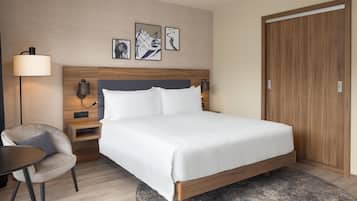 Una habitación de hotel con cama, mesitas de noche, una silla y una obra de arte en la pared.