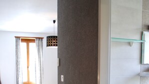 A hotel room with a bed, a bathroom with a sink, and a window with curtains.