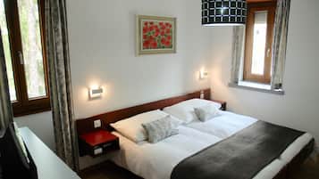 A double bed with white linens, a wooden headboard, and two bedside tables with red and white lamps.
