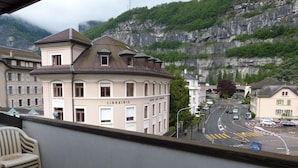 A building with a sign reading "LIBRAIRIE" and a view of a street with cars and a mountain in the background.