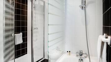 Un baño moderno con ducha envuelta en vidrio, bañera separada y mampara de cristal.