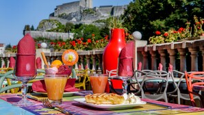 A table set with a glass of orange juice, a pastry, and a red vase. - Hotel La Solitude (Lourdes)