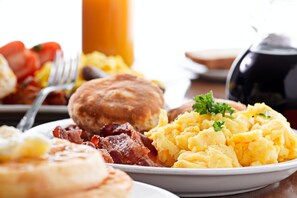 A breakfast plate with scrambled eggs, bacon, sausage, toast, and mashed potatoes. - Hotel La Solitude (Lourdes)