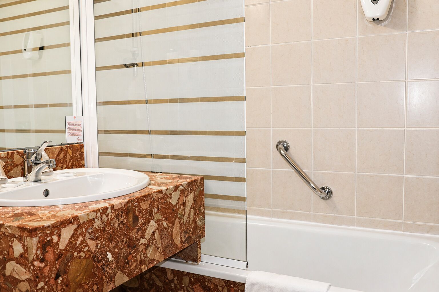 A bathroom with a marble sink, a handrail, and a bathtub.