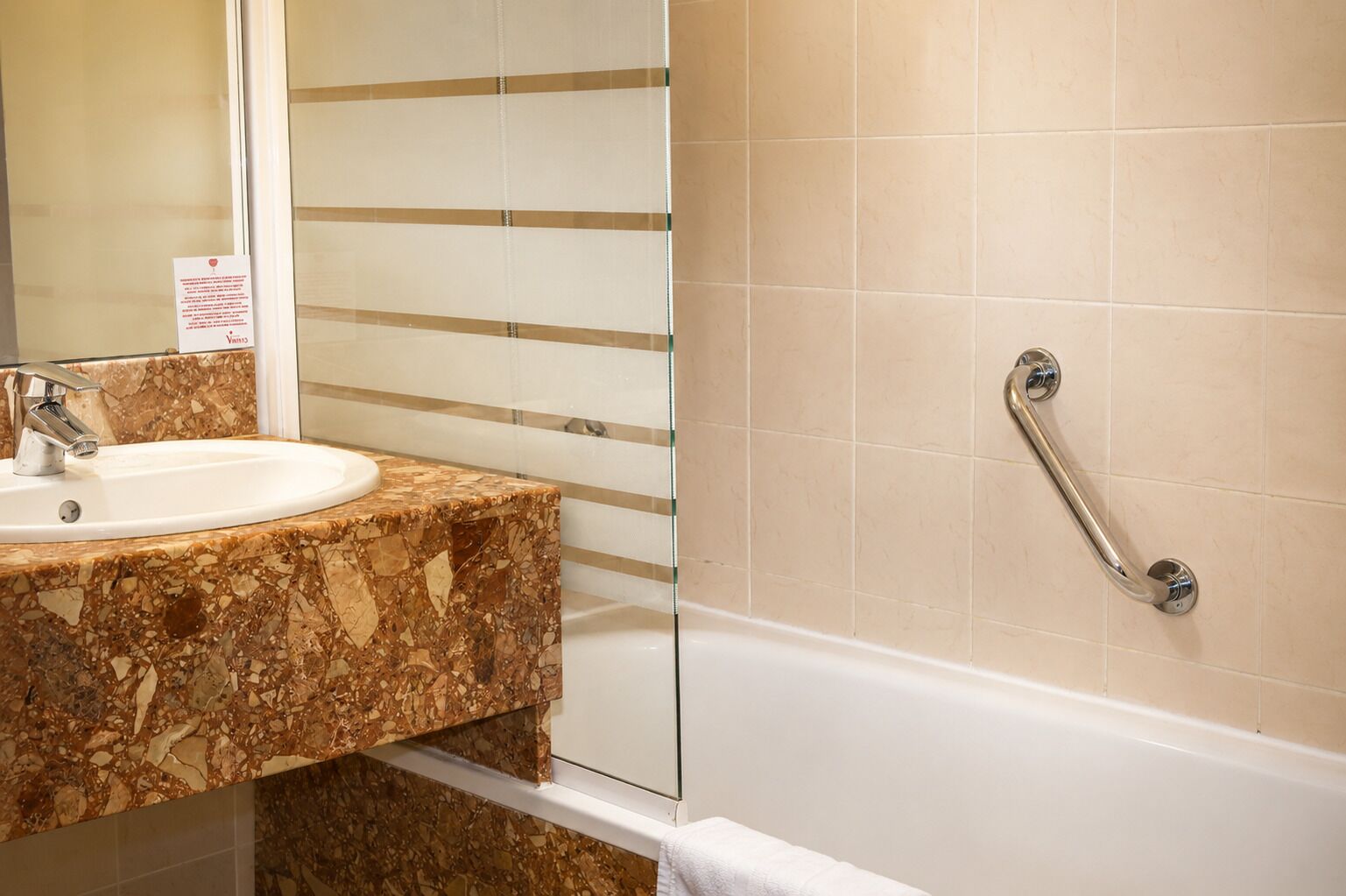 Un baño con lavabo, espejo y barra de apoyo.