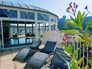A rooftop pool area with lounge chairs and a glass-enclosed structure. - Hotel La Solitude (Lourdes)