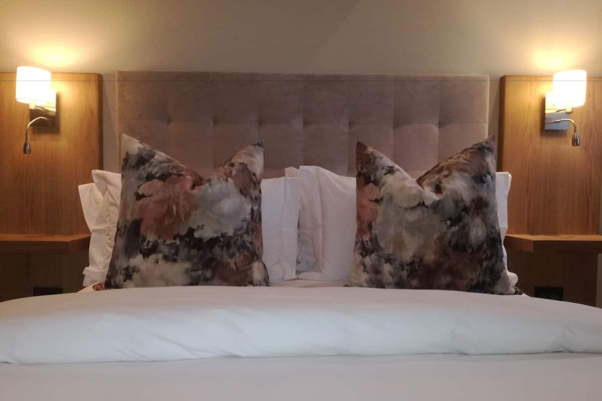 A hotel room with a large bed, two nightstands, and a tufted headboard.