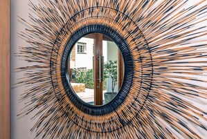 A circular mirror with a sunburst pattern on the wall.