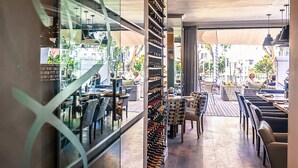 An indoor dining area with tables and chairs, a wine rack, and a view through a glass wall. - Sugar Hotel (Cape Town)