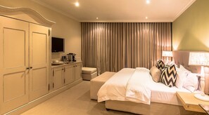 A hotel room with a bed, a TV, a minibar, and a large window with curtains. - Sugar Hotel (Cape Town)