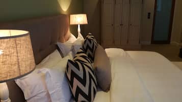 Una cama bien hecha con cabecera, lámpara y armario en una habitación de hotel.
